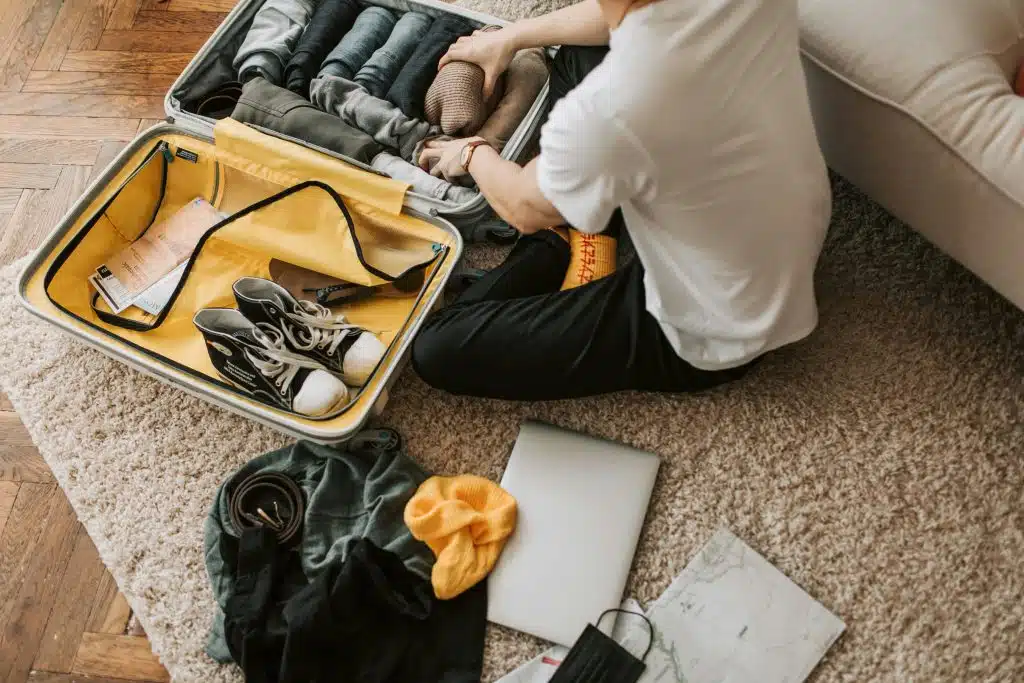 Person packing a suitcase on carpet.