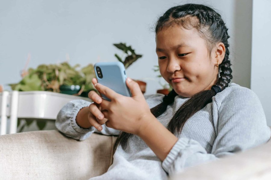Girl using smartphone on couch.